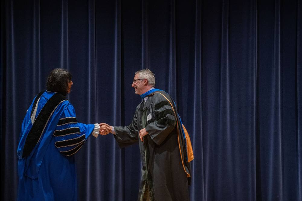 President Mantella shakes hands with man on stage